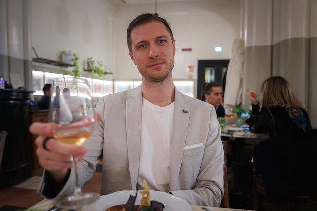 Geavanceerde man in licht pak geniet van wijn in de elegante eetkamer van een hotel in Rome.