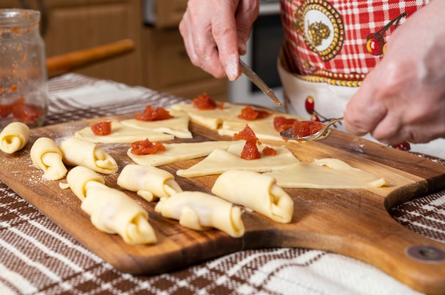 Gebak en bakken concept. Vrouw die zelfgemaakte broodjes met jam thuis voorbereidt