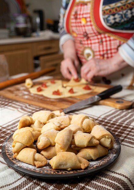 Gebak en bakken concept. Vrouw die zelfgemaakte broodjes met jam thuis voorbereidt