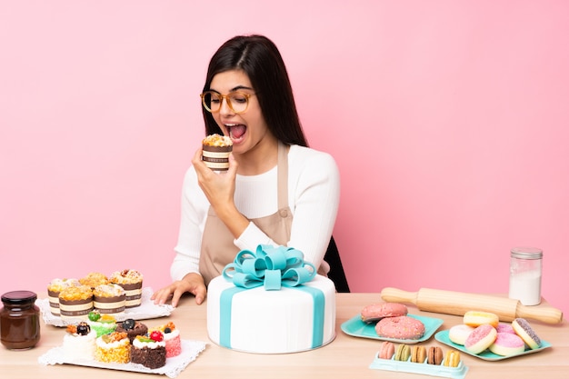 Gebakjechef-kok met een grote cake in een lijst over roze muur