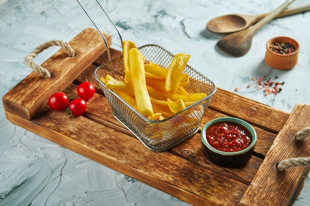 Gebakken aardappel dip in een metalen mand op een houten dienblad. Overheerlijk fastfood. Close-up weergave frietjes