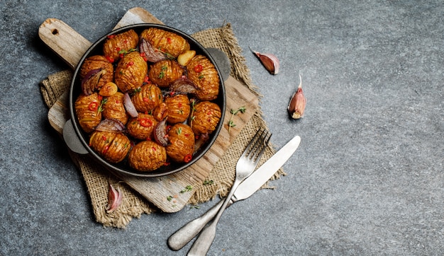 Gebakken aardappelen in gietijzeren pan met ui, knoflook en kruiden