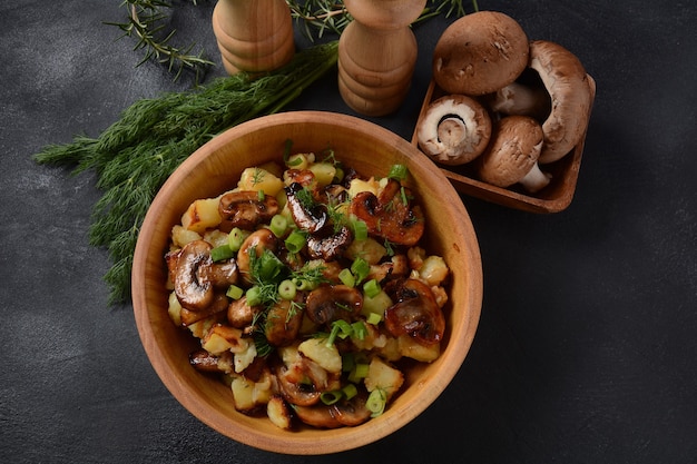 Gebakken aardappelen met champignons in een houten kom. Rustieke stijl.