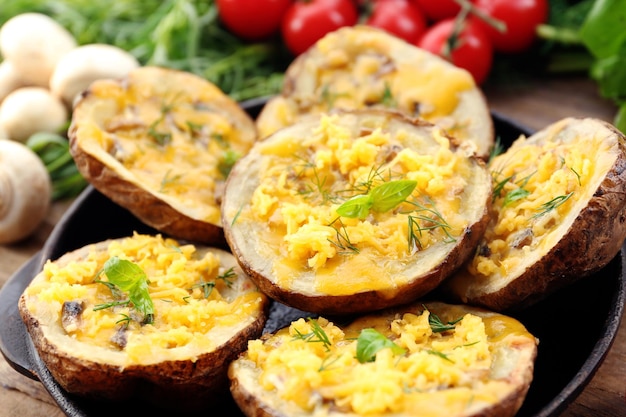 Gebakken aardappelen met kaas en champignons op plaat close-up