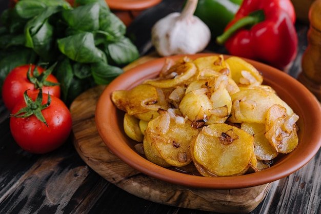 Gebakken aardappelen met uien op houten dienblad