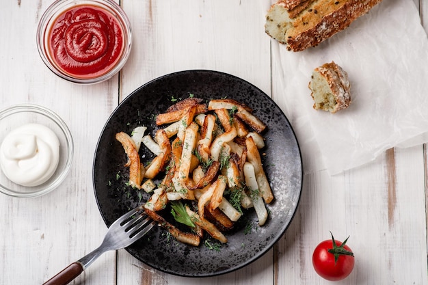 Gebakken aardappelen op een witte houten achtergrond met mayonaise ketchup tomaten