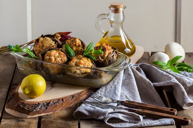 Gebakken artisjokken gekookt in de oven met champignons, ui en gehakt en kaas, gezond eten, Italiaanse keuken en mediterraan gerecht van Puglia