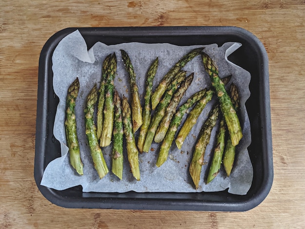 Gebakken asperges in ovenschaal koken in oven op houten tafelblad