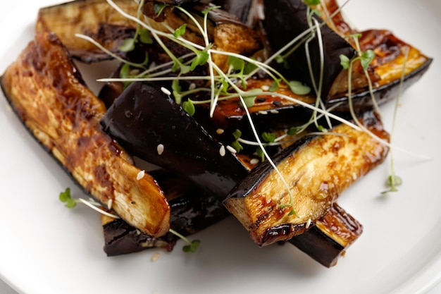 Foto gebakken aubergine geglazuurd met saus honing op witte plaat en marmeren achtergrond heerlijk veganistisch eten