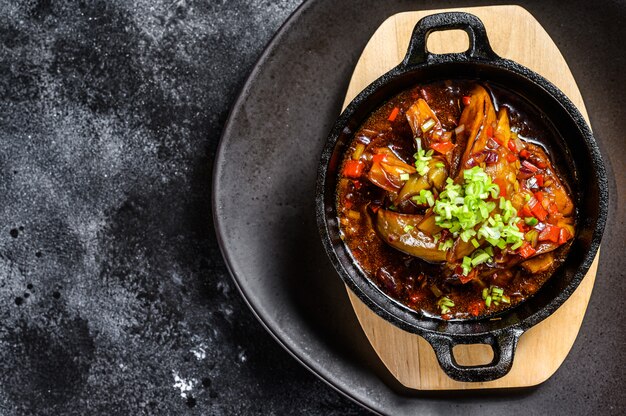 Gebakken aubergine in tomatensaus. Zwarte achtergrond. Bovenaanzicht. Kopieer ruimte