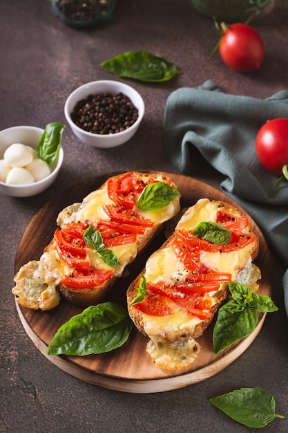 Gebakken brioche sandwiches met tomaten mozzarella en basilicum op een snijplank verticaal zicht