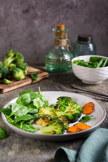 Gebakken broccoli wortelen en spinazie bladeren op een bord Gezonde voeding Verticale weergave