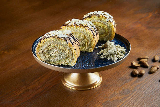 Gebakken broodjes met halva en amandelen op een blauw bord op een houten tafel. turkse zoetigheden. thee of koffie bakken