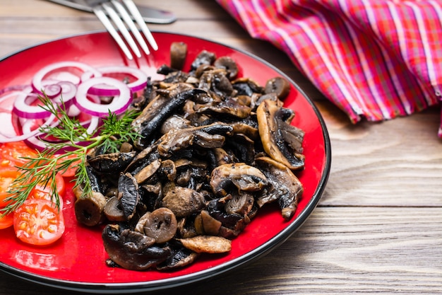 gebakken champignons, cherry tomaten en uien op een bord op een houten tafel