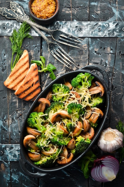 Gebakken champignons en broccoli met kaas in een zwarte pan Bovenaanzicht Vrije ruimte voor uw tekst Rustieke stijl