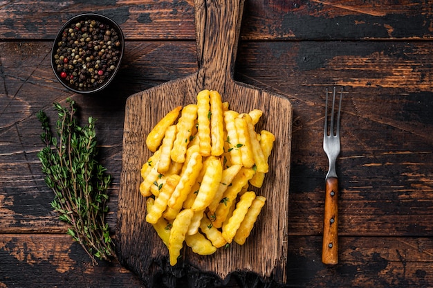 Gebakken Crinkle Frieten Aardappelsticks of chips op een houten plank