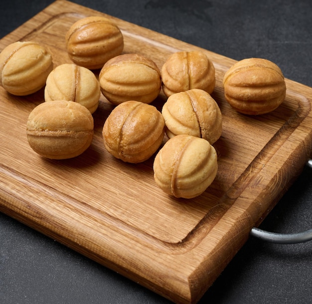 Gebakken dessertnoten met gecondenseerde melk op een houten bord, bovenaanzicht