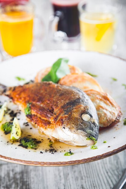 gebakken dorado op een bord met gestoofde groentensaus