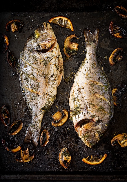 Gebakken dorado vis in knoflook dille saus met champignons en citroen. Plat lag. Bovenaanzicht