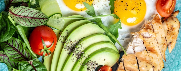 Gebakken ei Close-up zicht op de Kip gegrilde filet verse tomaten komkommers en avocado Ketogeen dieet ontbijt Voedsel recept achtergrond