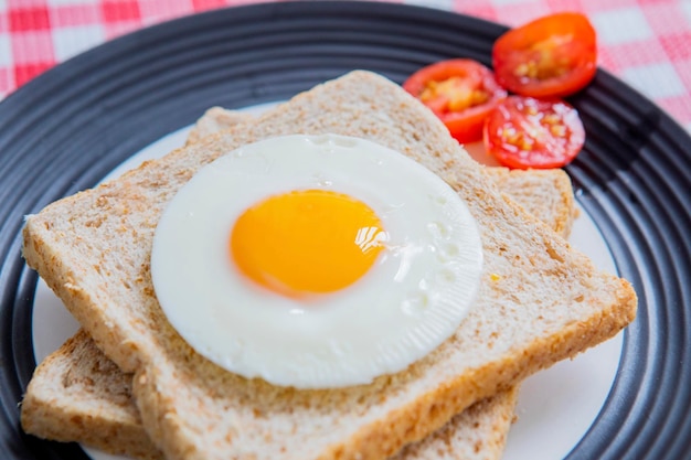 Gebakken ei en volkoren toast met gesneden tomaten