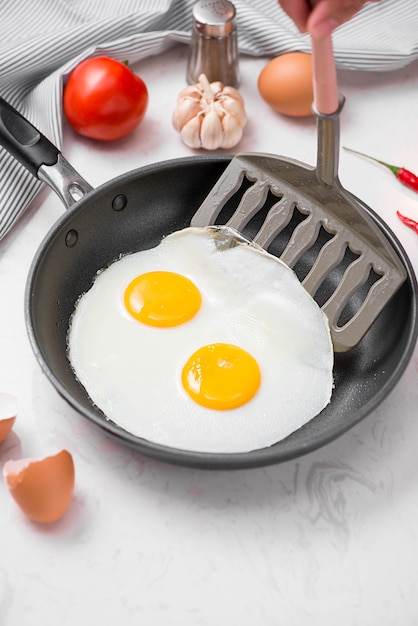 Gebakken eieren in een koekenpan met kerstomaatjes en brood voor het ontbijt