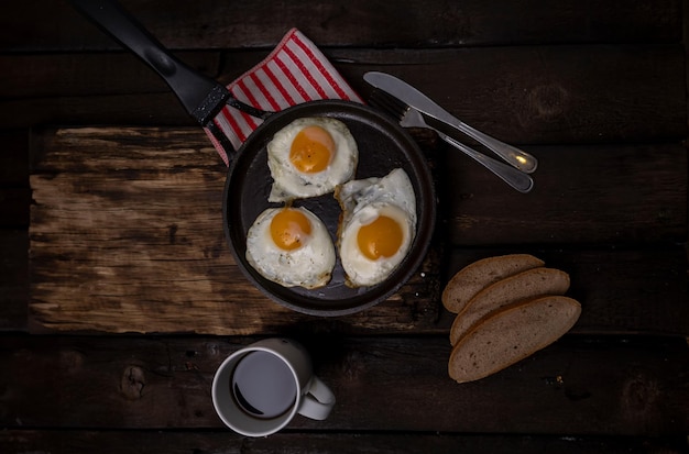 Foto gebakken eieren in een pan met groenten en kruiden op een zwarte achtergrond