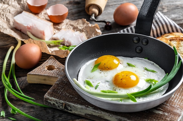 Foto gebakken eieren in koekenpan met varkensreuzel, brood en groene verenuien
