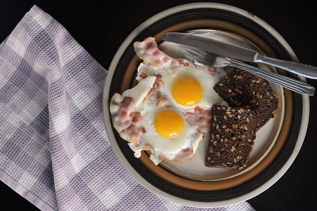 Gebakken eieren met hele dooier, spek en toast - bovenaanzicht plat gelegd