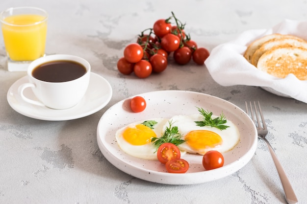 Foto gebakken eieren met kruiden, rode tomaten, toast, koffie en vers sap