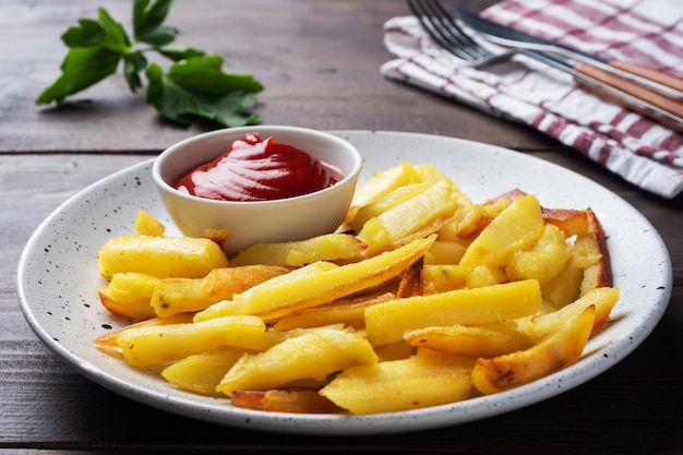 Gebakken Franse frietjesaardappelen met tomatenketchupsaus op een bord.