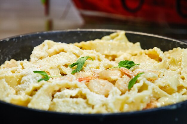 Gebakken garnalen met Italiaanse pasta, Parmezaanse kaas en kruiden in een pan.