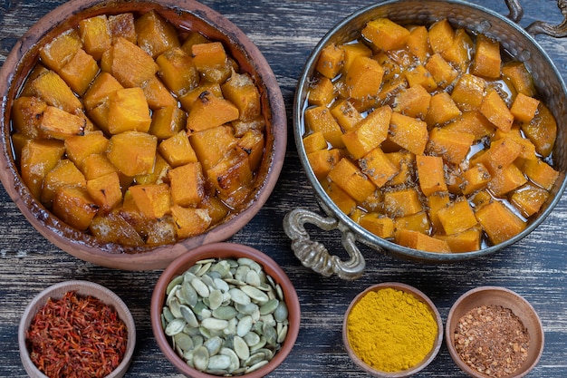 Gebakken gele pompoen met honing, anijs, olijfolie en kruiden op een bord op de houten tafel. Vegetarisch eten. Detailopname