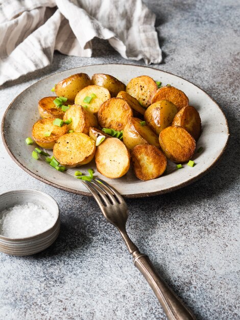 Gebakken geroosterde aardappelpartjes met lente-uitjes op vintage plaat op een grijze ondergrond