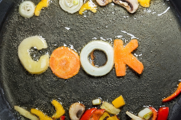 Gebakken groenten in de vorm van letters op een koekenpan in olie