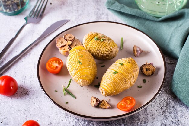 Gebakken hasselback-aardappelen met knoflook en rozemarijn op een bord Zelfgemaakte lunch