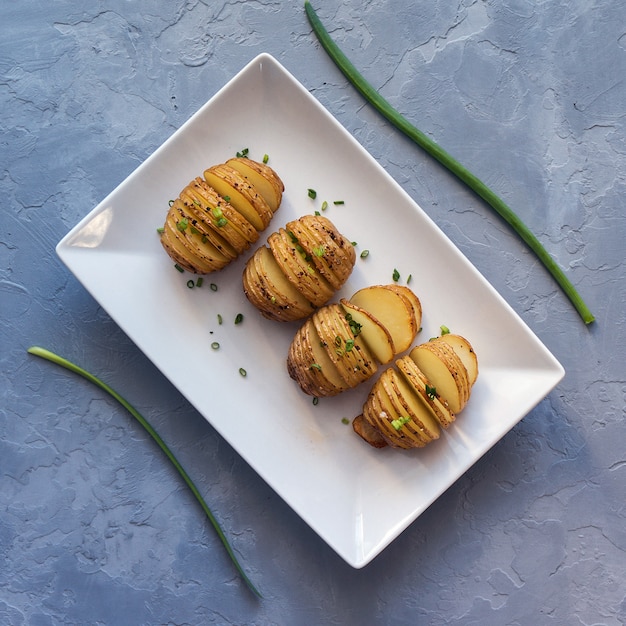 Gebakken hasselback-aardappelen met ui en kruiden. Bovenaanzicht