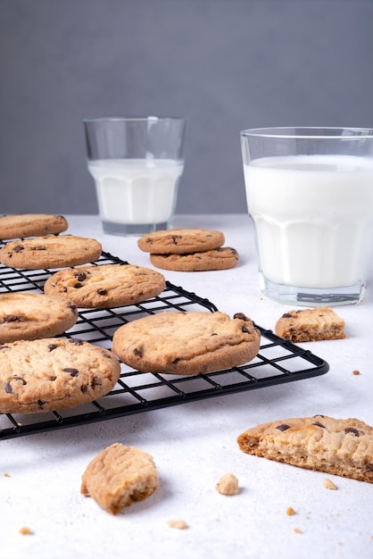 Gebakken havermoutkoekjes met chocoladeschilfers op een metalen koelrek en melk in een glas