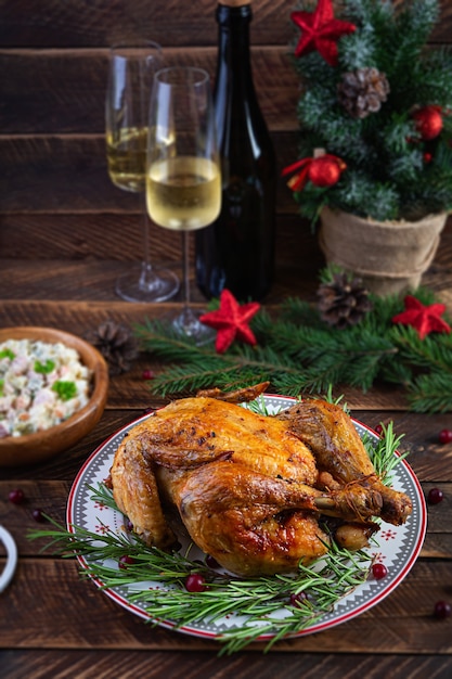 Gebakken hele kip of kalkoen voor Kerstmis. Nieuwjaarstafel met decoratie, huisgemaakte geroosterde kip, wijn en salade