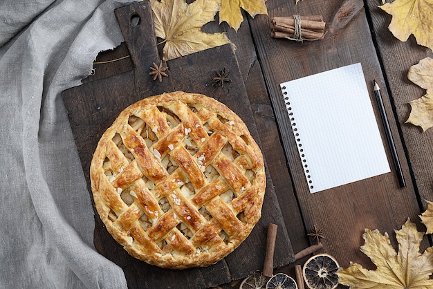 Gebakken hele ronde appeltaart op een bruin houten bord, bladerdeeg