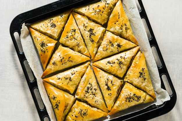 Gebakken in de oven indiase samosa gemaakt met filodeeg met pittige aardappelen en groenten met zwarte sesamzaadjes. straat traditioneel fastfood