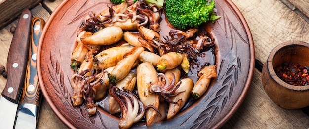Gebakken inktvis gevuld met broccoli en champignons. Smakelijke zeevruchten op houten achtergrond. Lange banner