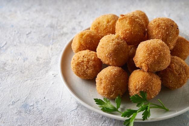 Foto gebakken kaasballetjes, voorgerecht met kruiden en sauzen in een plaat op een grijze tafel