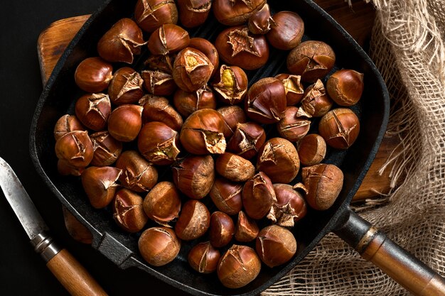 Foto gebakken kastanjes in een pan op een houten standaard