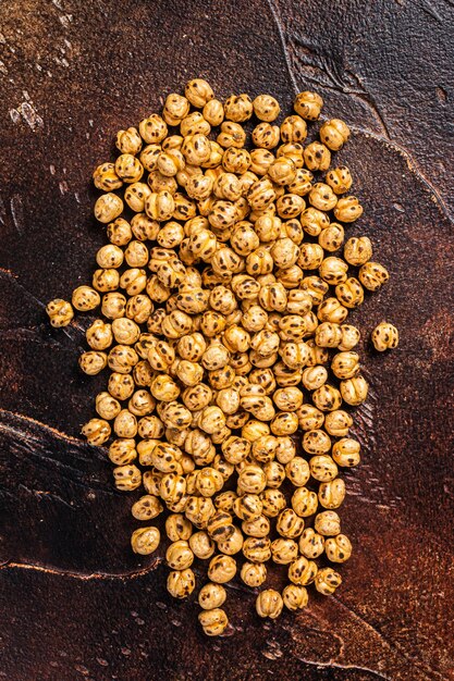 Gebakken kikkererwten met kurkuma, geroosterde pittige kikkererwten of Indiase chana of chole. Donkere achtergrond. Bovenaanzicht.