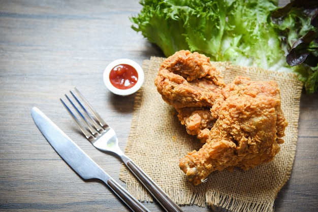 Gebakken kip knapperig op zak met vork ketchup en salade sla groente op eettafel