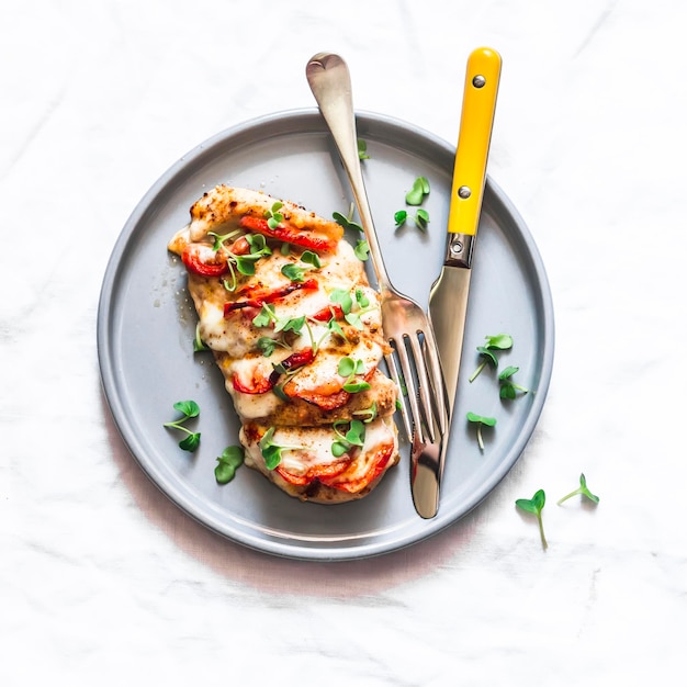 Gebakken kipfilet gevuld met tomaten en mozzarella op een lichte achtergrond bovenaanzicht