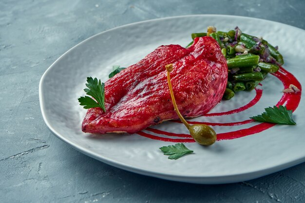 Gebakken kipfilet in bessensaus met asperges en garnituur met pinda's in een witte plaat