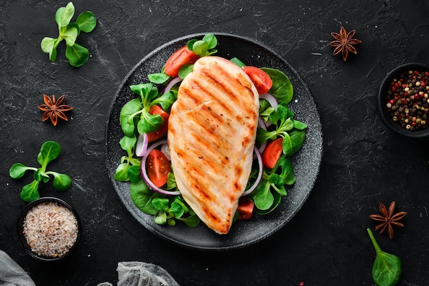 Gebakken kipfilet met groenten In een zwarte plaat op een houten achtergrond Bovenaanzicht Vrije ruimte voor uw tekst Plat leggen