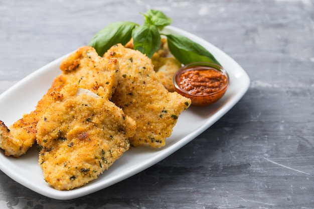 Gebakken kipfilet met saus op witte schotel op keramiek